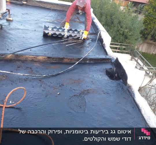 אדם מיישם יריעות איטום על גג שטוח